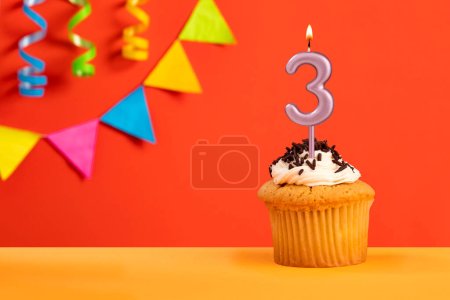 Téléchargez les photos : Bougie numéro 3 gâteau d'anniversaire sur fond orange avec bunting - en image libre de droit