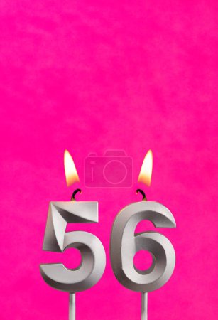 Photo for Candle 56 with flame - Silver anniversary candle on a fuchsia background - Royalty Free Image