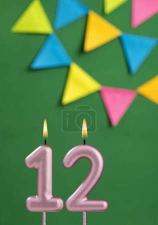Foto de Vela de cumpleaños número 12 - Celebración del aniversario en fondo de color verde - Imagen libre de derechos