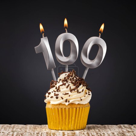 magdalena de cumpleaños con número 100 vela - Celebración sobre fondo oscuro