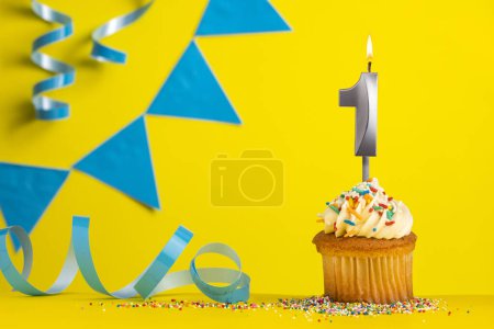 Téléchargez les photos : Bougie d'anniversaire numéro 1 avec cupcake - fond jaune avec des fanions bleus - en image libre de droit