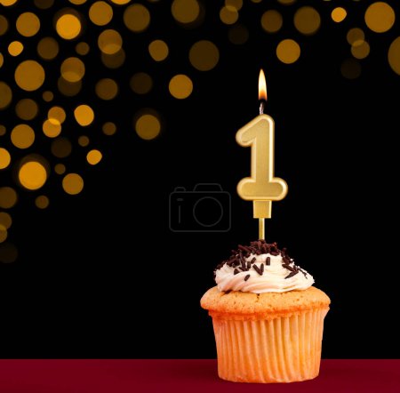 Téléchargez les photos : Bougie d'anniversaire numéro 1 - Cupcake sur fond noir avec des lumières hors foyer - en image libre de droit