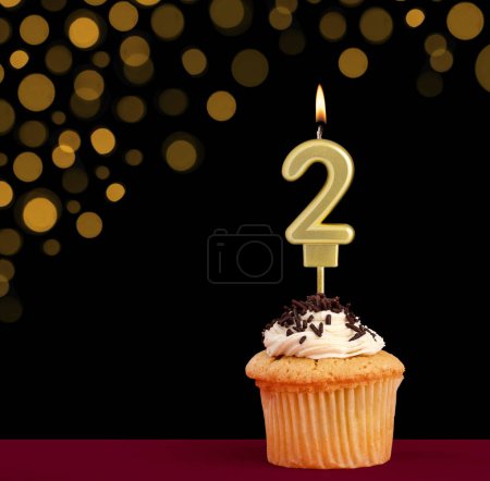 Photo for Birthday candle with cupcake - Number 2 on black background with out of focus lights - Royalty Free Image