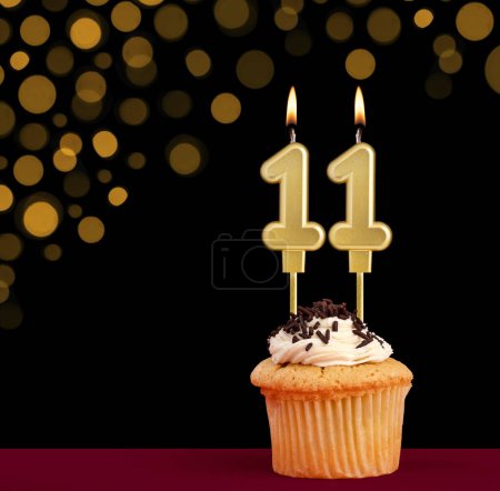 Photo for Number 11 birthday candle - Cupcake on black background with out of focus lights - Royalty Free Image