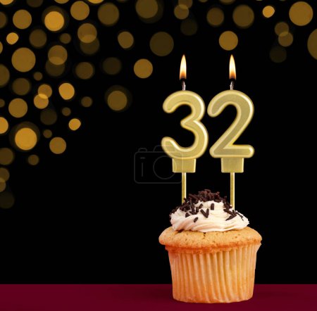 Photo for Birthday candle with cupcake - Number 32 on black background with out of focus lights - Royalty Free Image