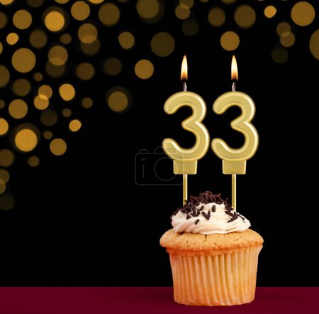 Photo for Number 33 birthday candle - Cupcake on black background with out of focus lights - Royalty Free Image
