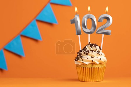 Foto de Tarta de cumpleaños con número de vela 102 - Fondo naranja - Imagen libre de derechos