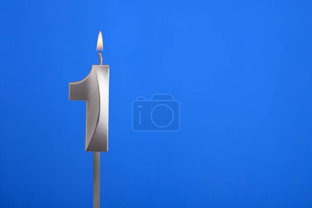 Téléchargez les photos : Bougie d'anniversaire numéro 1 - Carte de célébration sur fond bleu - en image libre de droit