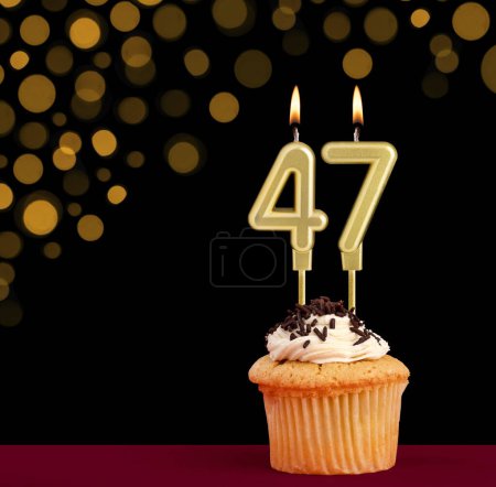 Photo for Number 47 birthday candle - Cupcake on black background with out of focus lights - Royalty Free Image