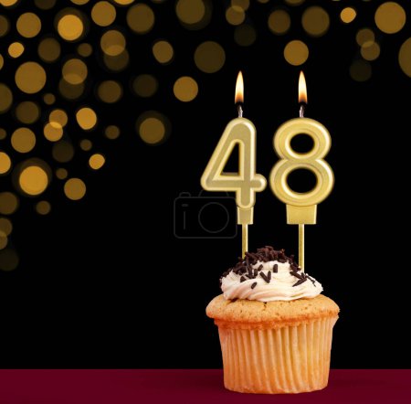 Photo for Birthday candle with cupcake - Number 48 on black background with out of focus lights - Royalty Free Image
