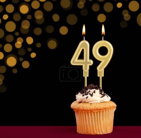 Photo for Number 49 birthday candle - Cupcake on black background with out of focus lights - Royalty Free Image
