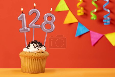 Foto de Número 128 Vela - Cumpleaños cupcake sobre fondo naranja con bunting - Imagen libre de derechos