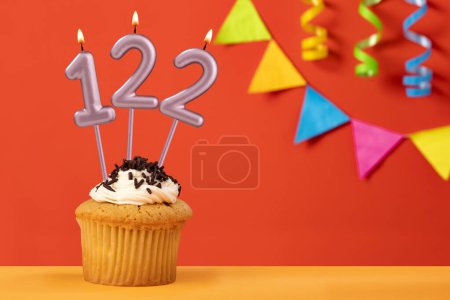 Foto de Número 122 Vela - Cumpleaños cupcake sobre fondo naranja con bunting - Imagen libre de derechos