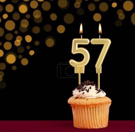 Photo for Number 57 birthday candle - Cupcake on black background with out of focus lights - Royalty Free Image