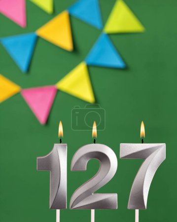 Foto de Tarjeta de cumpleaños vertical con número 127 vela Fondo verde con banderines - Imagen libre de derechos