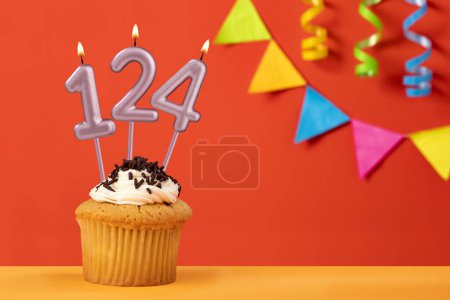 Foto de Número 124 Vela - Cumpleaños cupcake sobre fondo naranja con bunting - Imagen libre de derechos