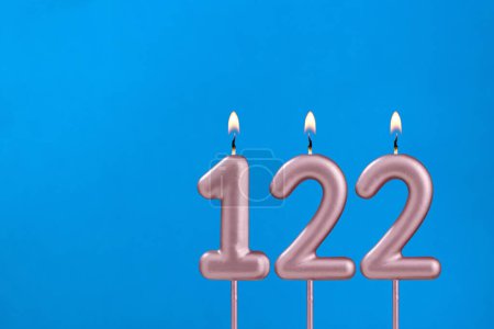 Number 122 - Burning anniversary candle on blue foamy background