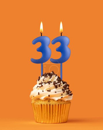 Foto de Vela azul número 33 - Pastel de cumpleaños sobre fondo naranja - Imagen libre de derechos