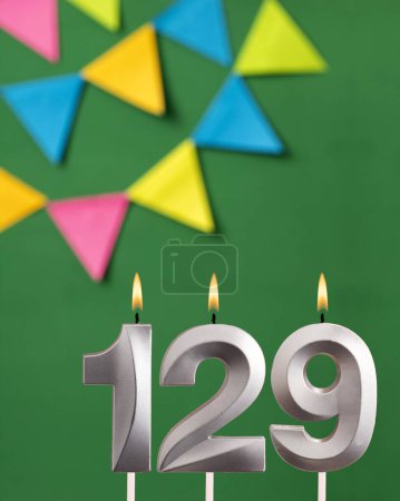Foto de Tarjeta de cumpleaños vertical con número 129 vela Fondo verde con banderines - Imagen libre de derechos