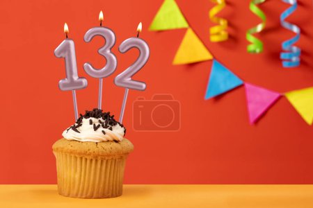 Foto de Número 132 vela - Cumpleaños cupcake sobre fondo naranja con bunting - Imagen libre de derechos