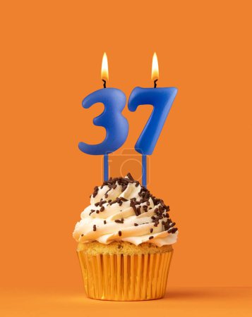 Foto de Vela azul número 37 - Pastel de cumpleaños sobre fondo naranja - Imagen libre de derechos