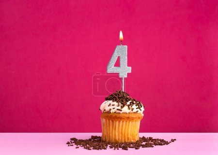 Célébration d'anniversaire avec la bougie numéro 4 - cupcake au chocolat sur fond rose