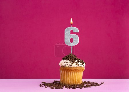 Célébration d'anniversaire avec la bougie numéro 6 - cupcake au chocolat sur fond rose