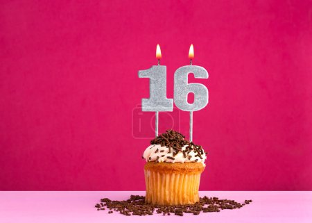 Célébration d'anniversaire avec bougie numéro 16 - cupcake au chocolat sur fond rose