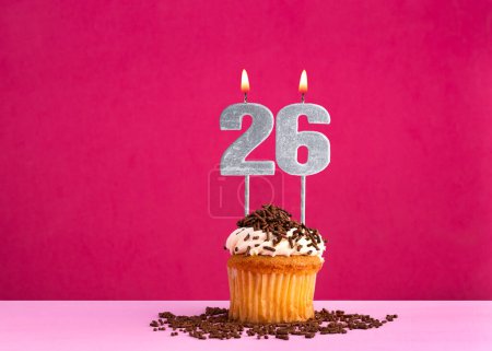 Célébration d'anniversaire avec la bougie numéro 26 - cupcake au chocolat sur fond rose