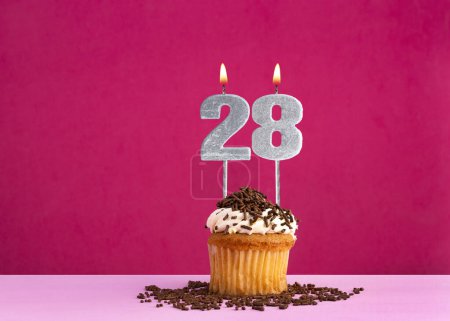 Célébration d'anniversaire avec la bougie numéro 28 - cupcake au chocolat sur fond rose