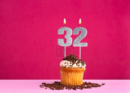 Birthday celebration with candle number 32 - Chocolate cupcake on pink background