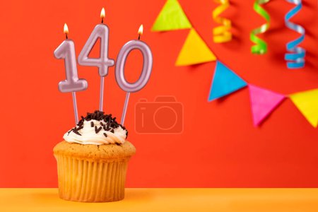 Foto de Número 140 vela - Cumpleaños cupcake sobre fondo naranja con bunting - Imagen libre de derechos