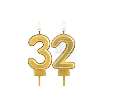 Golden number 32 birthday candle on white background