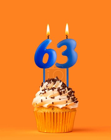 Foto de Vela azul número 63 - Pastel de cumpleaños sobre fondo naranja - Imagen libre de derechos