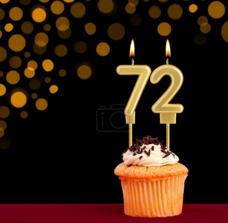 Vela de cumpleaños con magdalena - Número 72 sobre fondo negro con luces desenfocadas