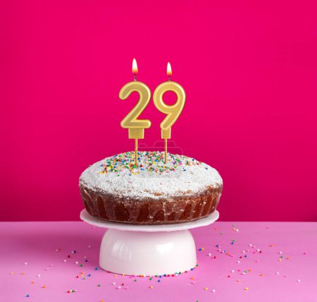 Birthday cake with number 29 candle on pink background