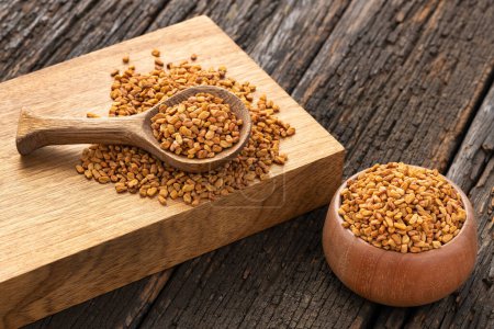 Organic fenugreek seeds in bowl and wooden spoon - Methi Dana