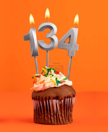Foto de Magdalena de cumpleaños con número 134 vela - Fondo de color naranja - Imagen libre de derechos