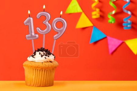 Birthday cupcake with number 139 candle - Sparkling orange background with bunting