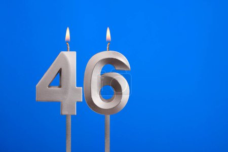 Cumpleaños número 46 - Vela encendida sobre fondo azul