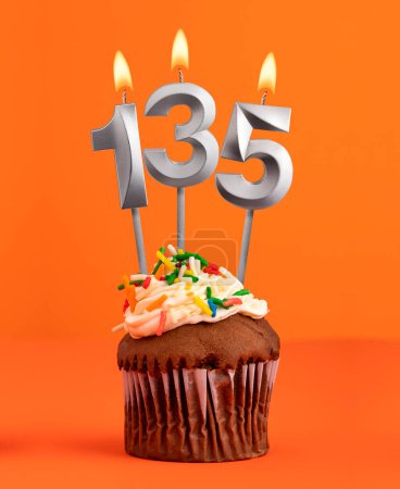 Nummer 135 Kerze - Geburtstagstorte auf orangefarbenem Hintergrund