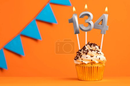 Birthday cupcake with candle number 134 - Orange background
