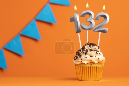 Photo for Birthday cupcake with candle number 132 - Orange background - Royalty Free Image
