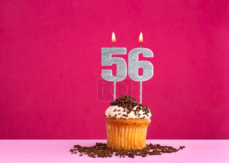 Birthday celebration with candle number 56 - Chocolate cupcake on pink background