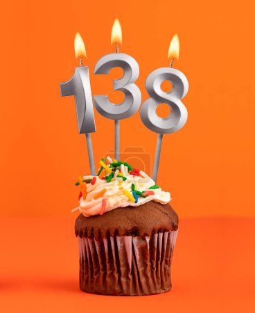 Foto de Magdalena de cumpleaños con número 138 vela - Fondo de color naranja - Imagen libre de derechos
