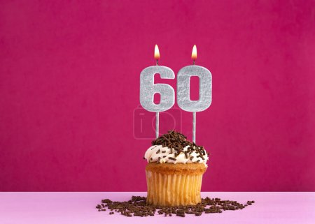 Geburtstagsfeier mit Kerze Nummer 60 - Schoko-Cupcake auf rosa Hintergrund