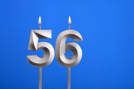 Geburtstag Nummer 56 - Kerze auf blauem Hintergrund angezündet