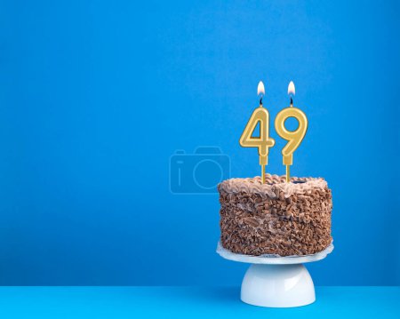 Celebración de cumpleaños con vela 49 - Pastel de chocolate sobre fondo azul