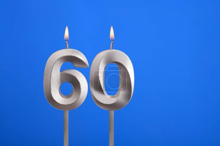 Geburtstag Nummer 60 - Kerze auf blauem Hintergrund angezündet