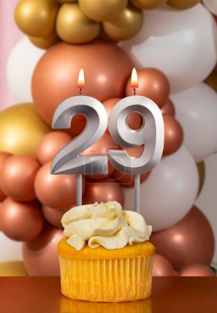 Cupcake with birthday candle on balloons background - Number 29